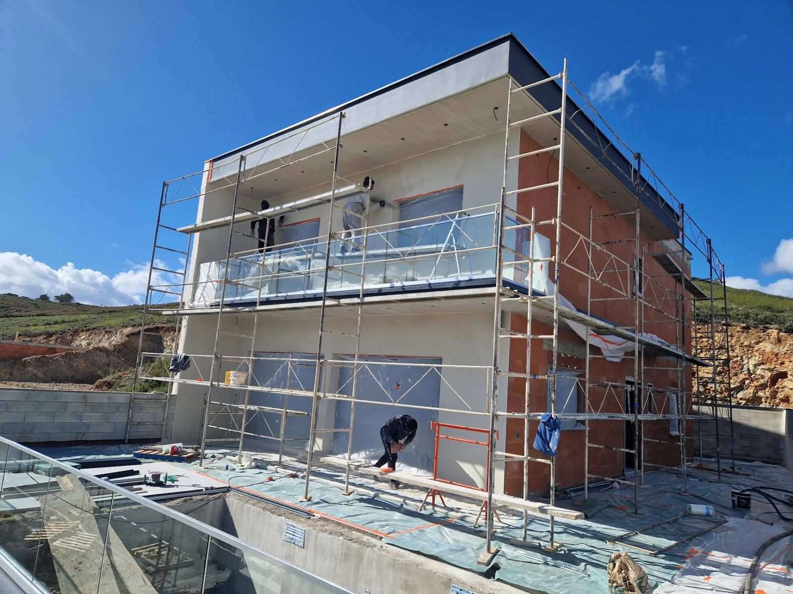 Façade de maison à étage en cours de finition sous échafaudage