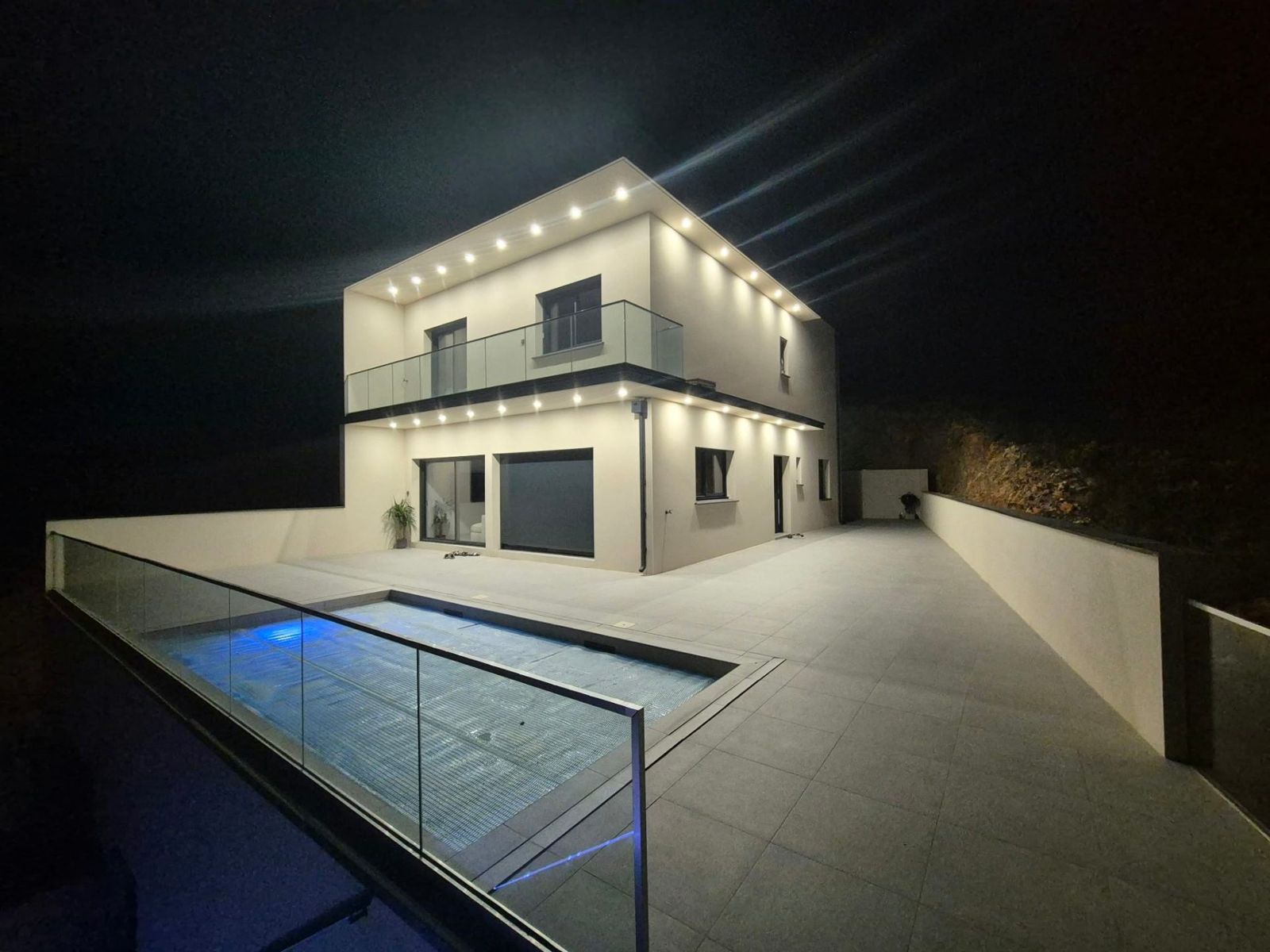Maison contemporaine éclairée de nuit, terrasse et piscine