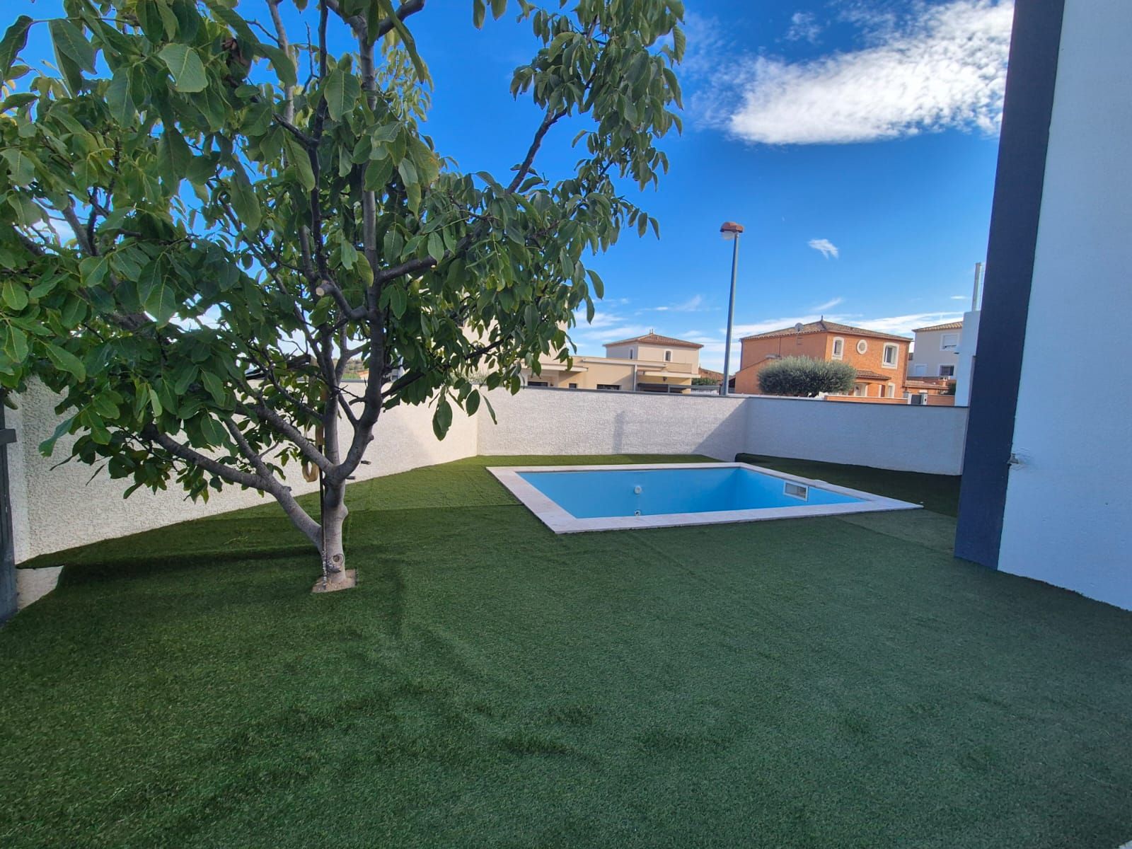 Jardin avec piscine et mur de clôture enduit