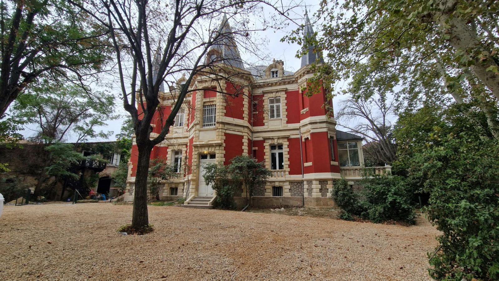 Demeure ancienne à façade rouge vue depuis le parc