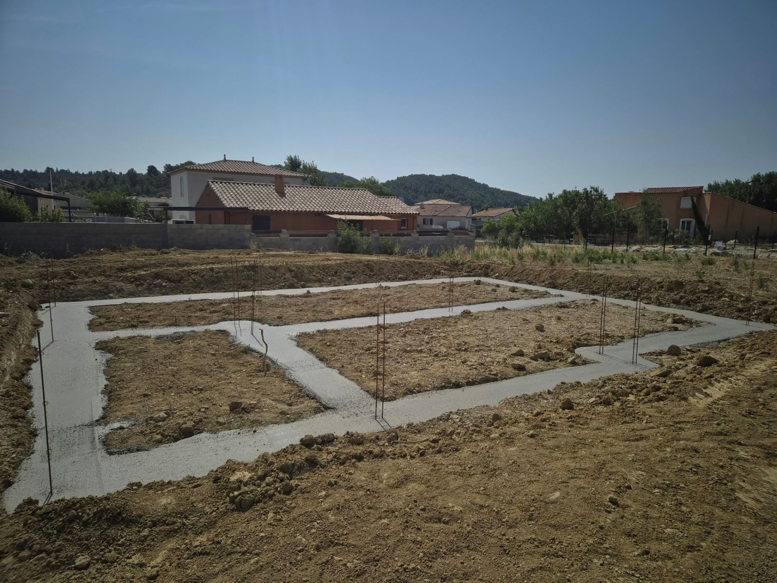 Semelles de fondation coulées dessinant l'emprise d'une future maison