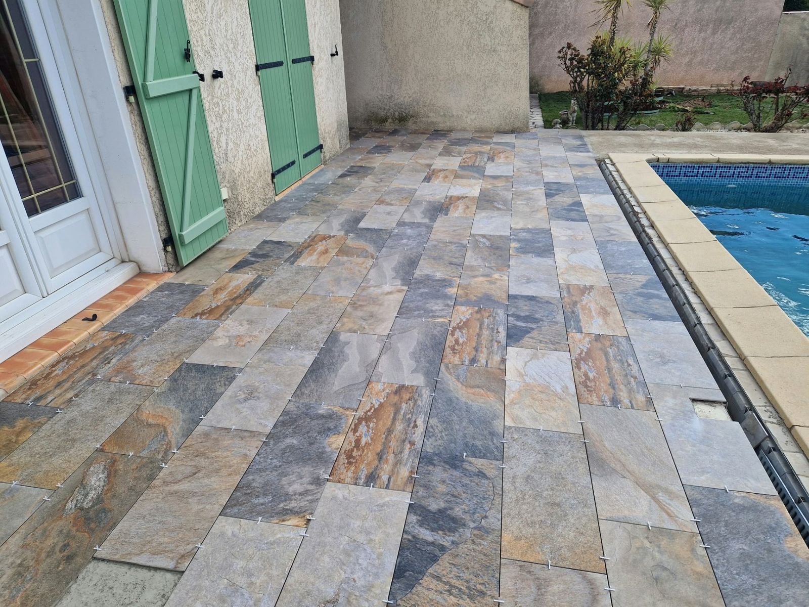 Terrasse en dallage pierre aux abords d'une piscine